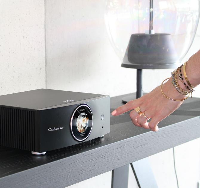 Cabasse Abyss Stereo Amplifier on a table with a hand reaching for the controls