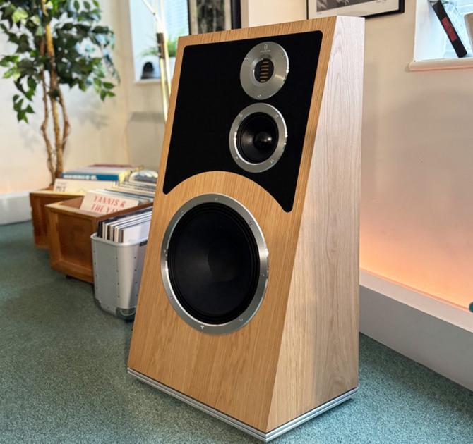 Audiovector Trapeze Ri in nordic oak.  Photo taken in the ripcaster showroom with a tall plant in the background and vinyl in wooden boxes