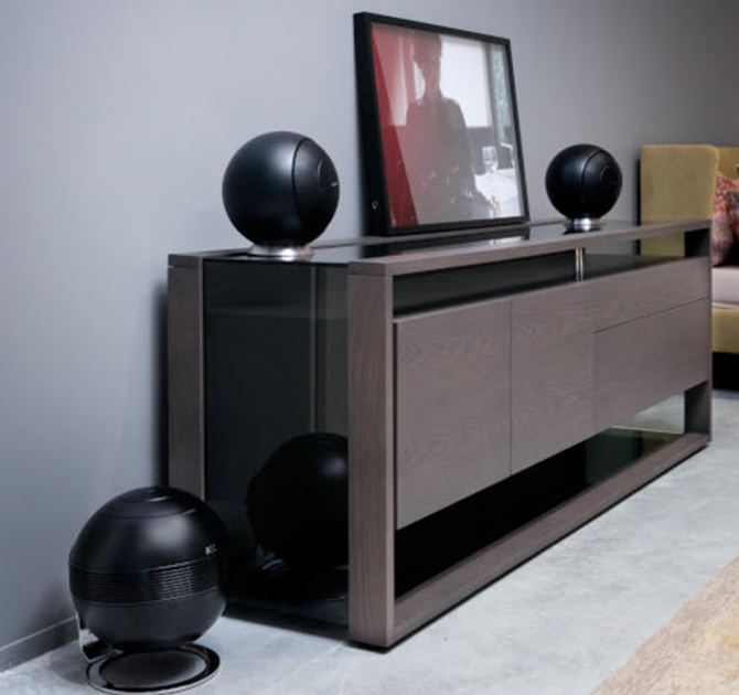 Cabasse Baltic 5 Sub System (on base) in black.  The sub is on the floor.  The Baltic 5s are on a wooden sideboard.  There's a sofa in the background.