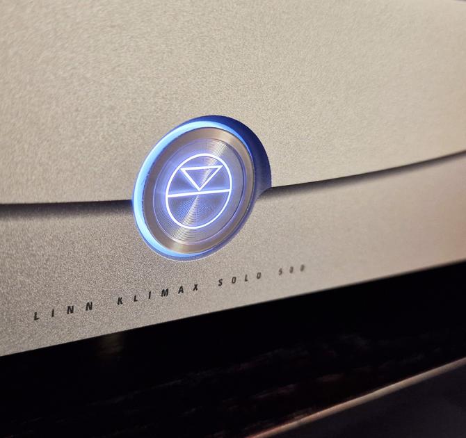 A close-up of the logo and words on the Klimax Solo 500 amplifier in silver.  Underneath the lit up logo are the words "Linn Klimax Solo 500"