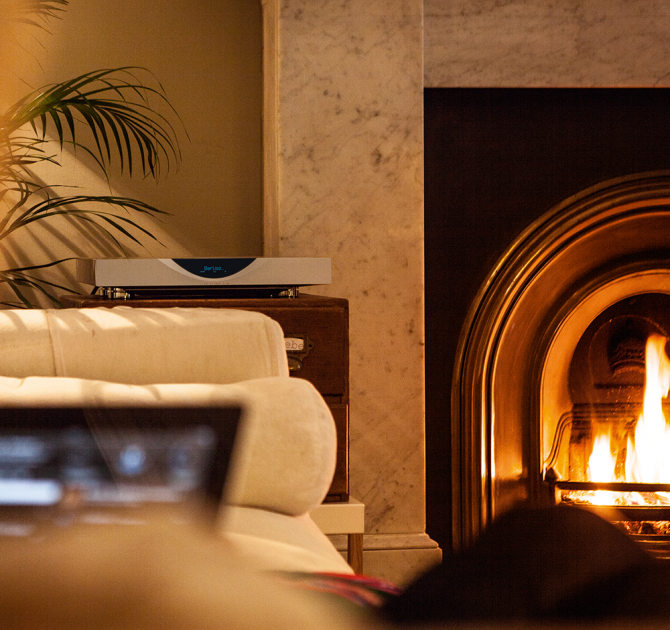 Linn Klimax DS on top of a wooden unit, next to a roaring fire.