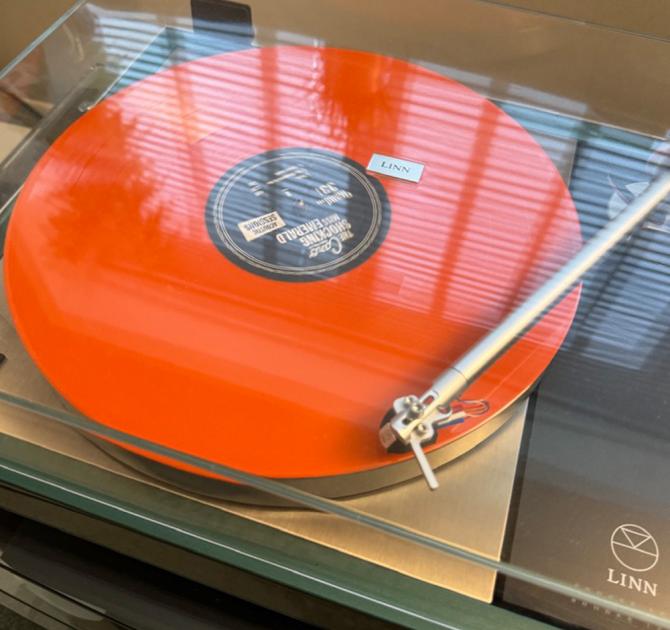 An orange record on the Majik LP12 turntable.  The lid is shut and the needle is on the first song.  The album is "The Shocking Miss Emerald"