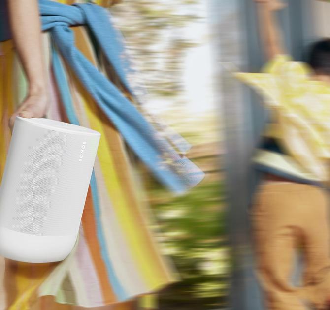 A woman in a summer dress carrying a white SONOS Move 2 Loudspeaker