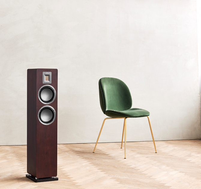 Audiovector QR3 in dark walnut with a chair beside it.