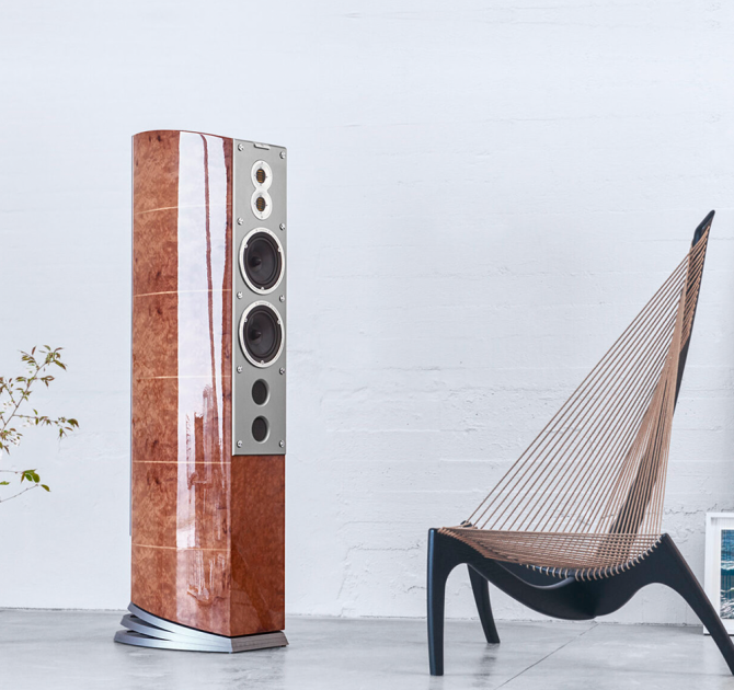 Audiovector R11 Arreté Loudspeaker in Madrona Burl in a white room beside an arty chair