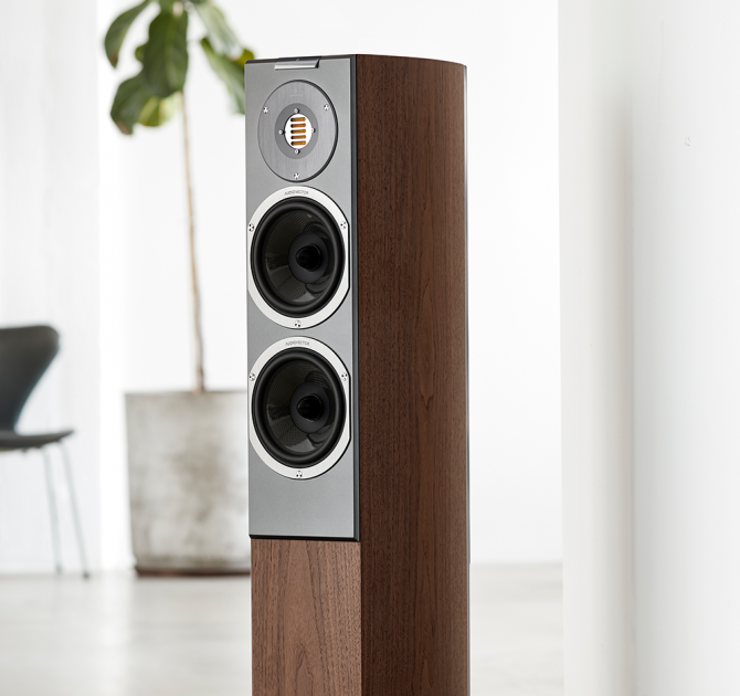 Audiovector R3 Arreté in Italian Walnut with a large houseplant and chair in the background