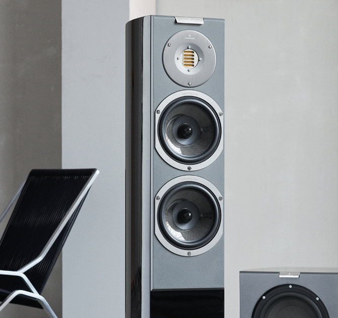 Audiovector R3 Arreté in black with a sub one side and a chair the other