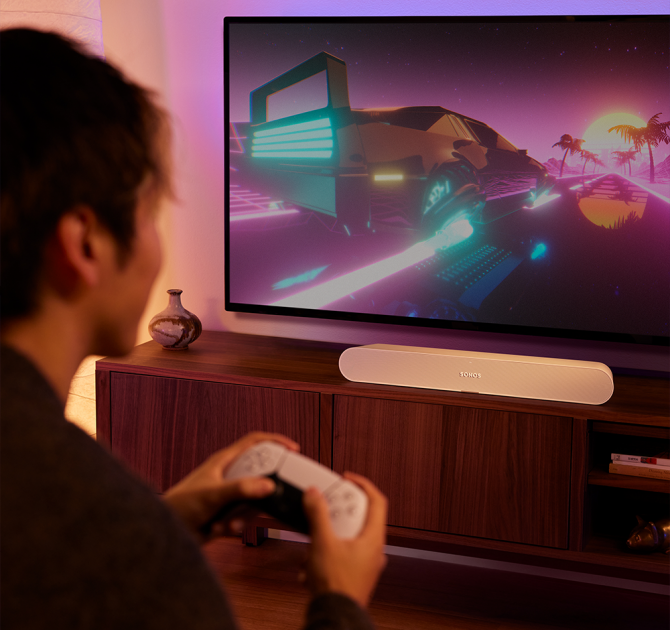 Sonos Ray Smart Soundbar in white with a partial view of a man gaming.