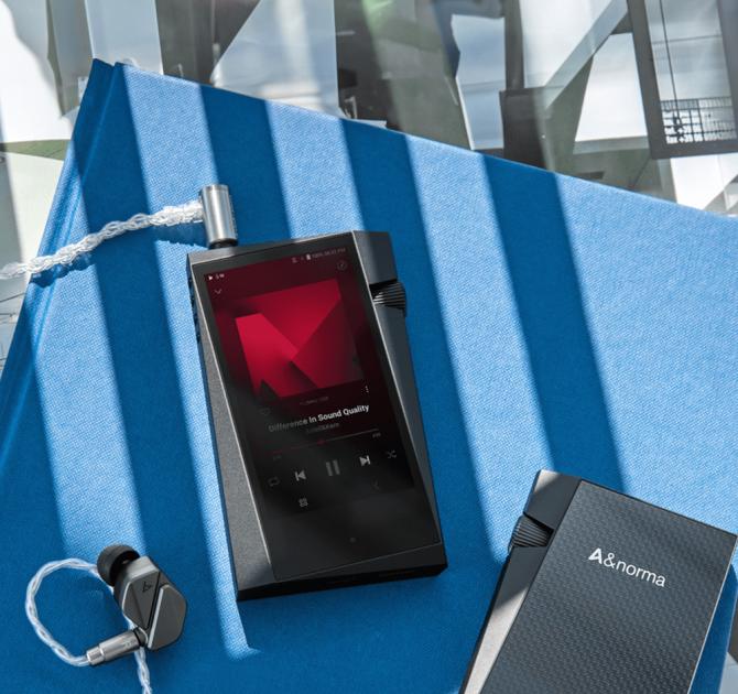 Astell & Kern A&norma SR35 Portable Music Player on a blue table beside some earphones