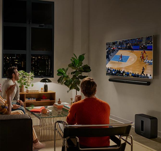 SONOS Arc Ultra Smart Soundbar in black underneath a wall mounted tv with some people watching football