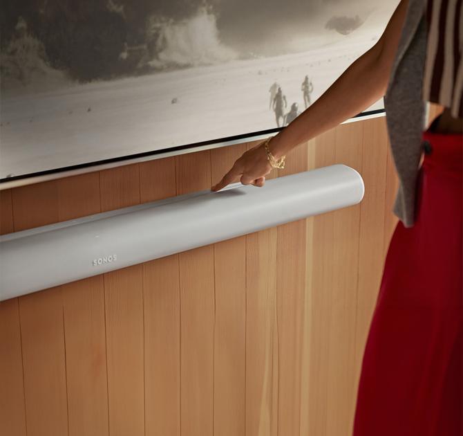 SONOS Arc Ultra Smart Soundbar in white with a woman touching the top of it