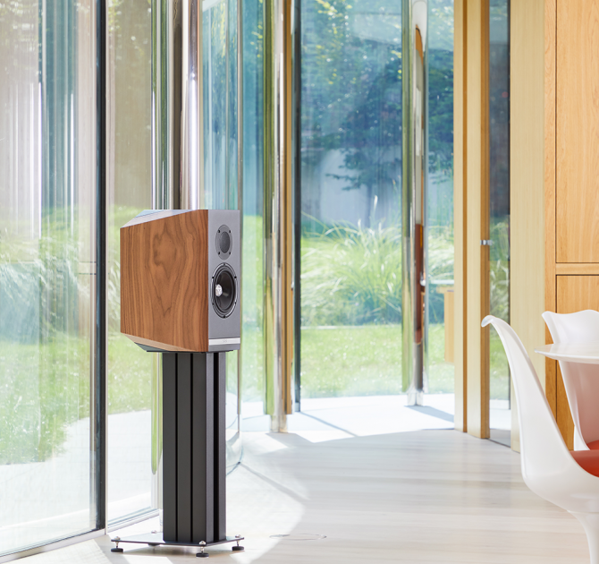 A single Titan 505 speaker on a stand with the grill off in front of large glass doors.