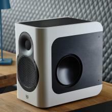 Kii Seven speaker in white on a wooden unit