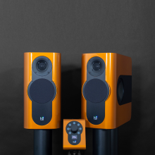 A pair of Kii Three Loudspeakers in Phoenix Orange with the Kii Controller on a black background