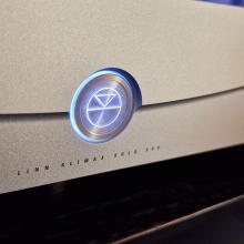 A close-up of the logo and words on the Klimax Solo 500 amplifier in silver.  Underneath the lit up logo are the words "Linn Klimax Solo 500"