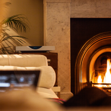 Linn Klimax DS on top of a wooden unit, next to a roaring fire.