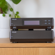 Melco N10/2 Digital Music Library in black.  One on top of the other on a sideboard with a plant beside it.