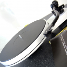 Project RPM 3 Carbon - Turntable in white at an angle with a product catalogue to the right.