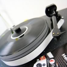 Project RPM 5 Carbon - Turntable in white pictured at an angle with a product catalogue.