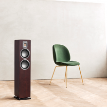 Audiovector QR3 in dark walnut with a chair beside it.