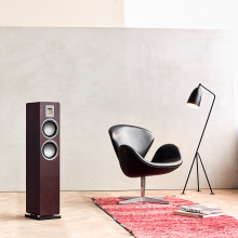 Audiovector QR3 in dark walnut with a chair and a floor lamp beside it.