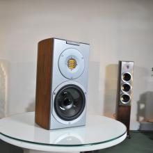 Audiovector R1 Arreté on a white table in the ripcaster showroom.  The floorstanding R8 is visible in the background.