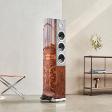 Audiovector R8 Arreté Loudspeaker in Italian Walnut Burl beside a table and shelves on the right