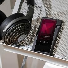 Astell & Kern A&norma SR35 Portable Music Player on a shelf beside a pair of headphones