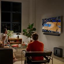 SONOS Arc Ultra Smart Soundbar in black underneath a wall mounted tv with some people watching football