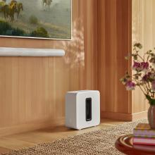 Sonos Sub Gen 4 in white on the floor with a tv wall mounted and a Sonos Arc underneath the TV.