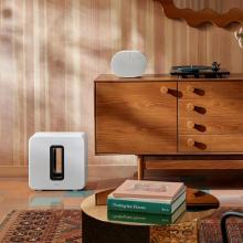 Sonos Sub Gen 4 in white on the floor beside a wooden side-board