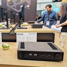 HiFi Rose RA280 in black on a wooden table with people in the background.  Photo taken at the Munich HiFi show in 2024