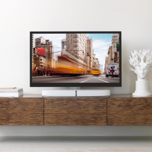 Flexson Adjustable TV Stand Playbase x1 with a Playbase and TV on a white stand.